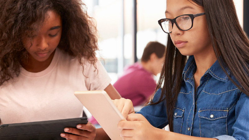 Two students working on tablets.