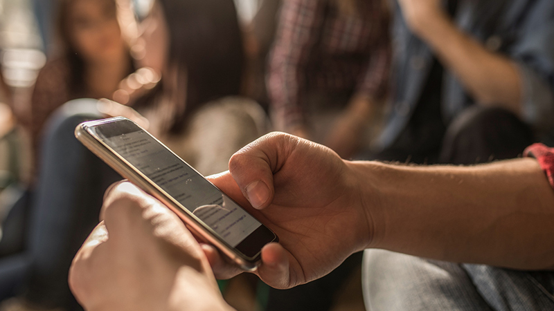 Teen browsing a news feed on his smartphone.