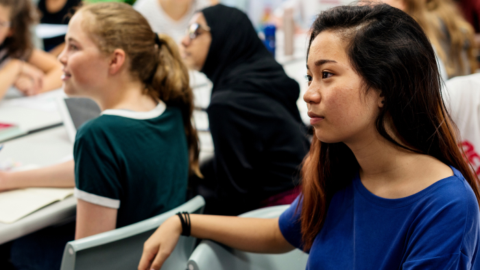 A diverse classroom of teens focuses on something out of the camera's range.