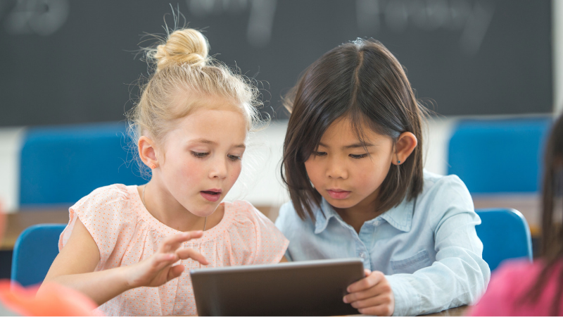 two kids looking at an ipad in class