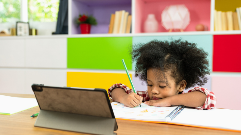 young african american girl drawing while looking at tablet