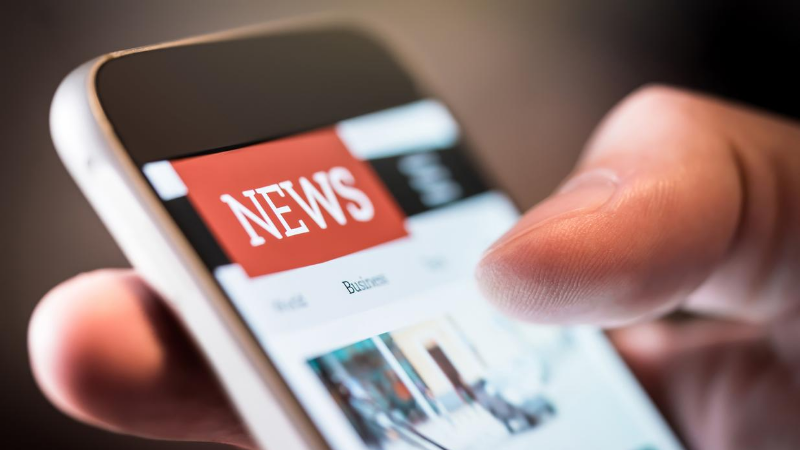 hand holding a phone with "News" on the screen