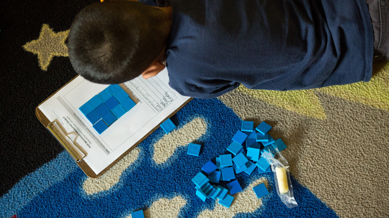 Student doing a math worksheet lying on a floor