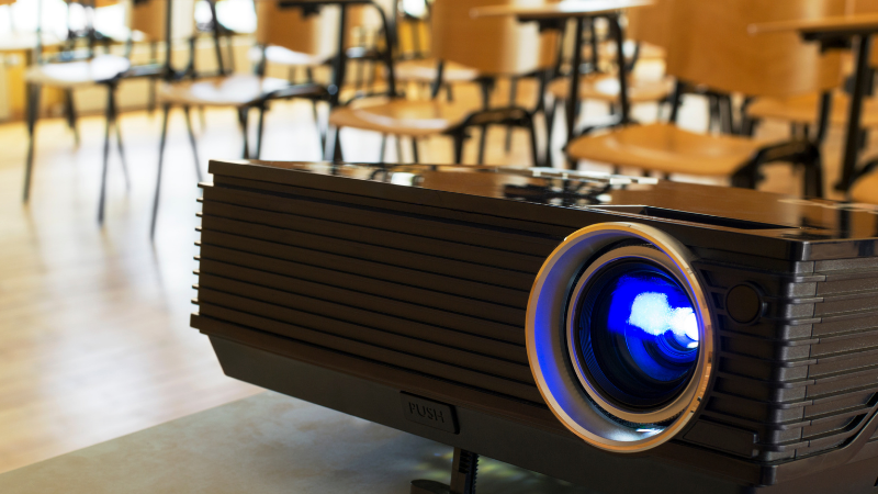 Projector in a classroom full of desks Projector in a classroom full of desks
