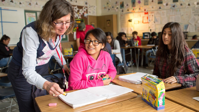 Photo of two students and a teacher working in a classroom