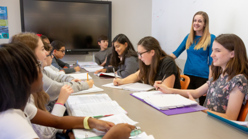 A teacher and students discussing in a classroom.