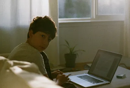 boy with laptop looks over shoulder