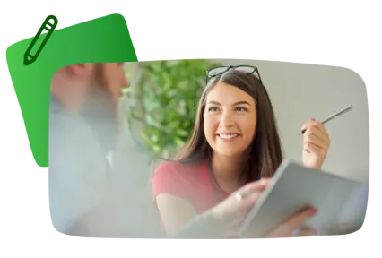 A photo of a teacher in a meeting, smiling and holding a pencil