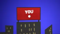 A billboard on top of a cityscape with a red background and white text that reads: "YOU"