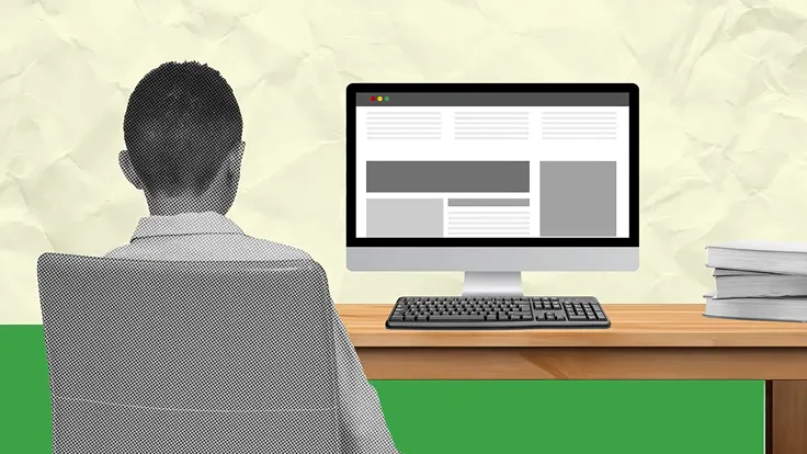 A student sits at a desk with a desktop computer open to a website.