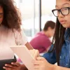 Two students working on tablets.