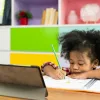 young african american girl drawing while looking at tablet